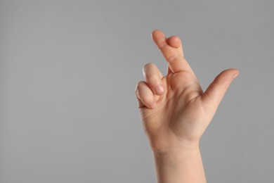 Child holding fingers crossed on light grey background, closeup with space for text. Good luck superstition