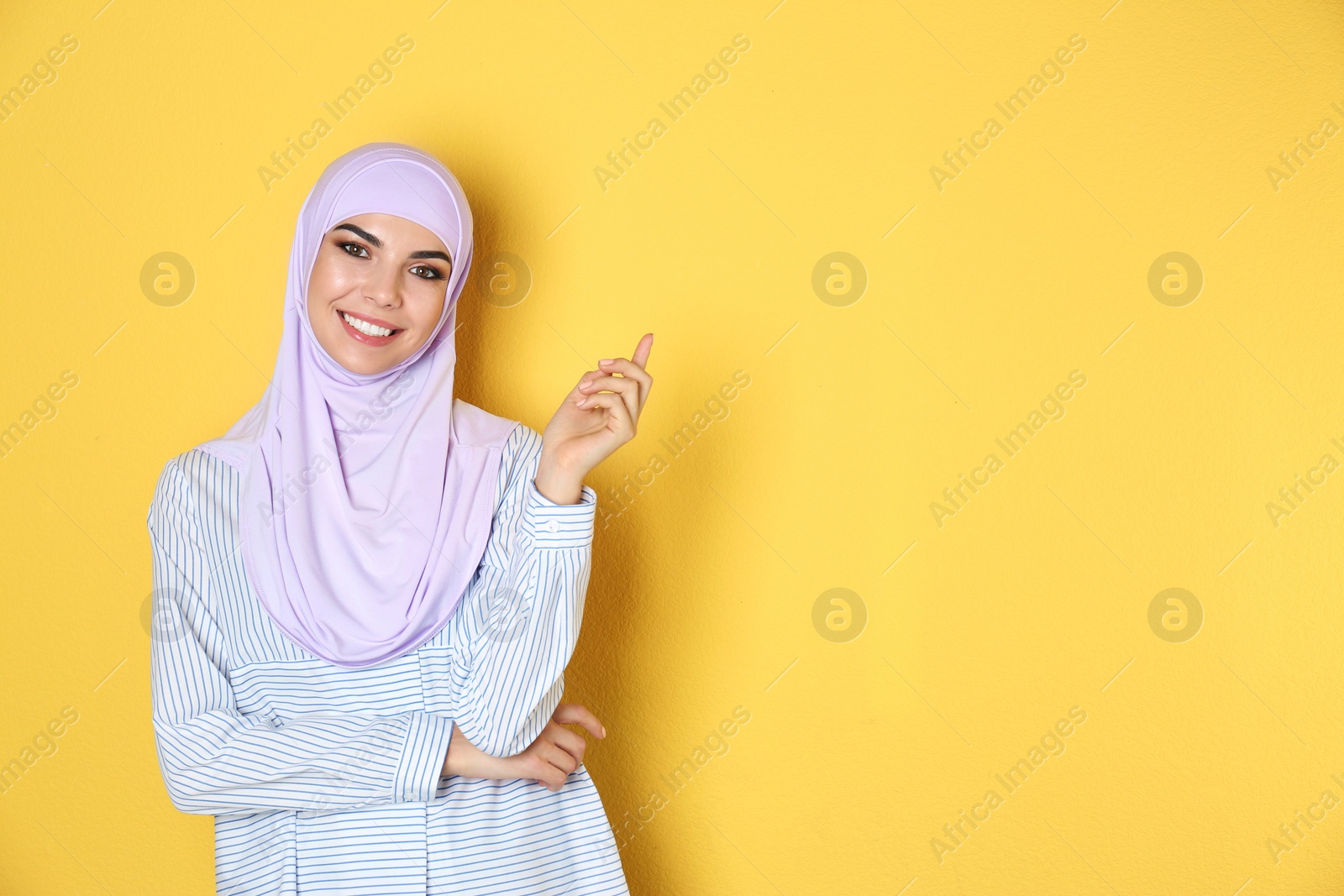 Photo of Portrait of young Muslim woman in hijab against color background. Space for text