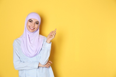 Photo of Portrait of young Muslim woman in hijab against color background. Space for text