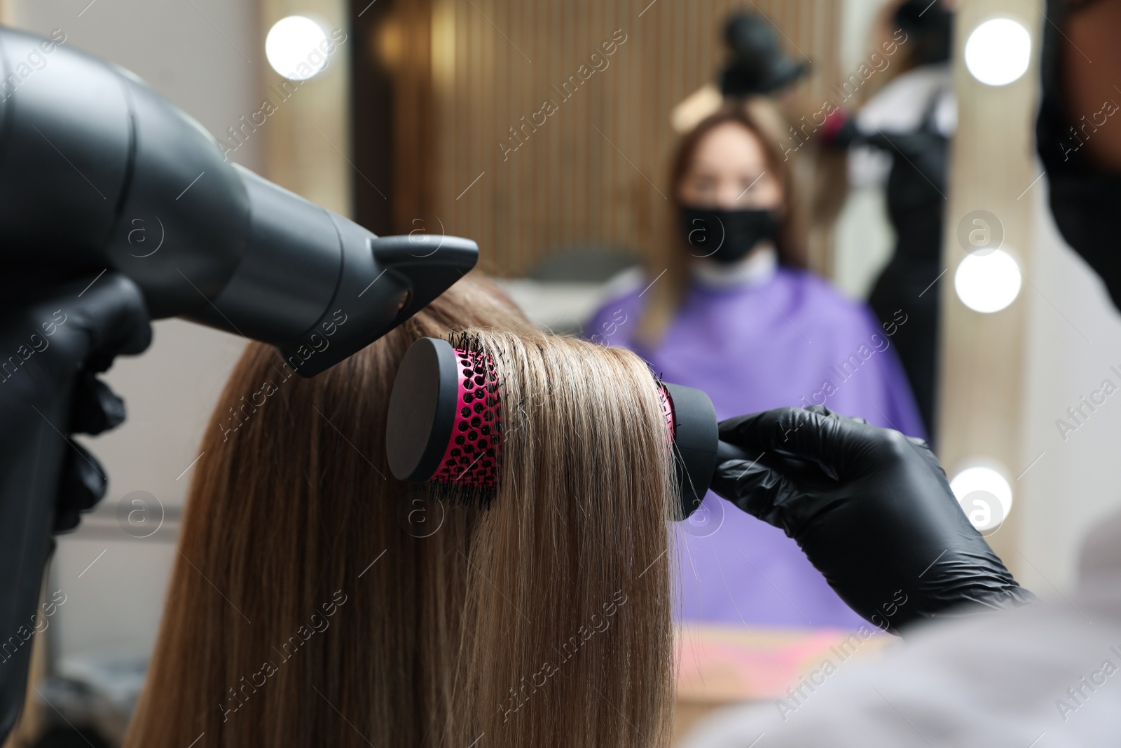 Photo of Professional stylist working with client in beauty salon, closeup. Hairdressing services during Coronavirus quarantine