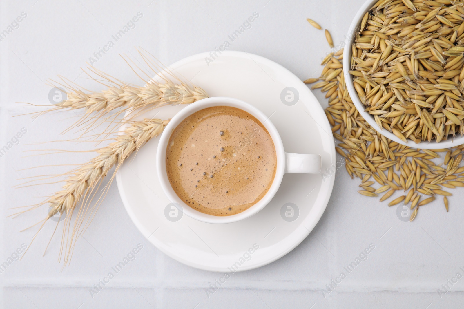 Photo of Cup of barley coffee, grains and spikes on white table, flat lay