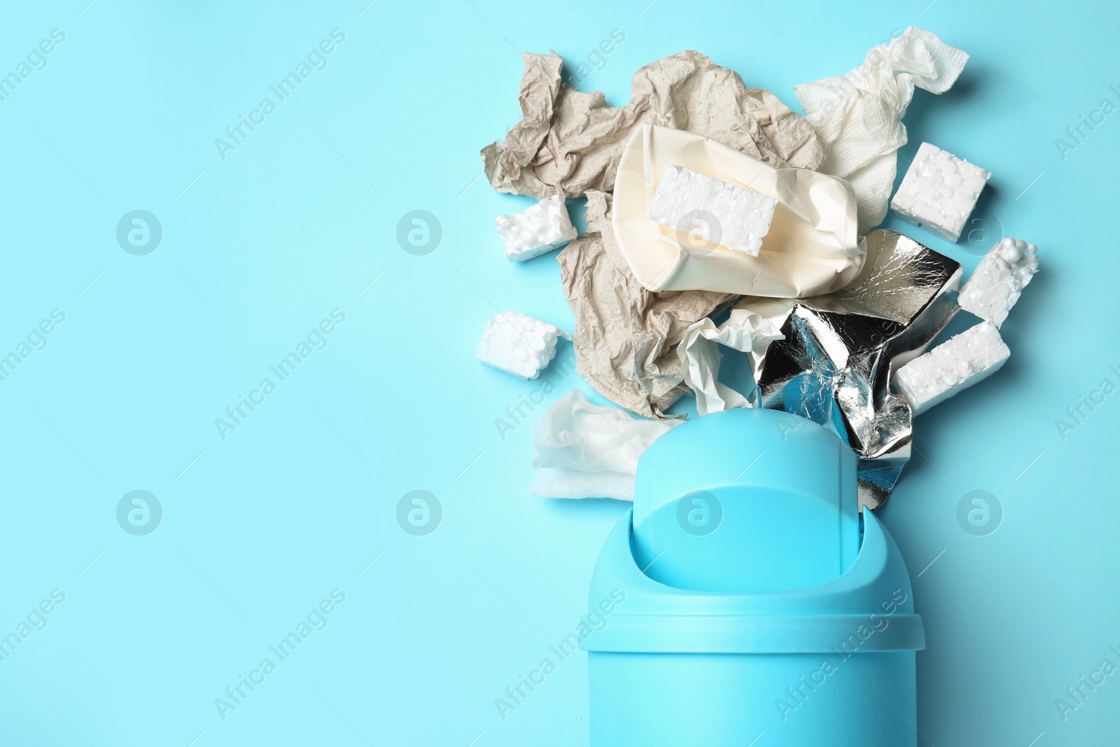 Photo of Trash bin and different garbage on color background, top view with space for text. Waste recycling concept