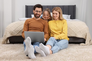 Photo of Happy family with laptop on floor at home