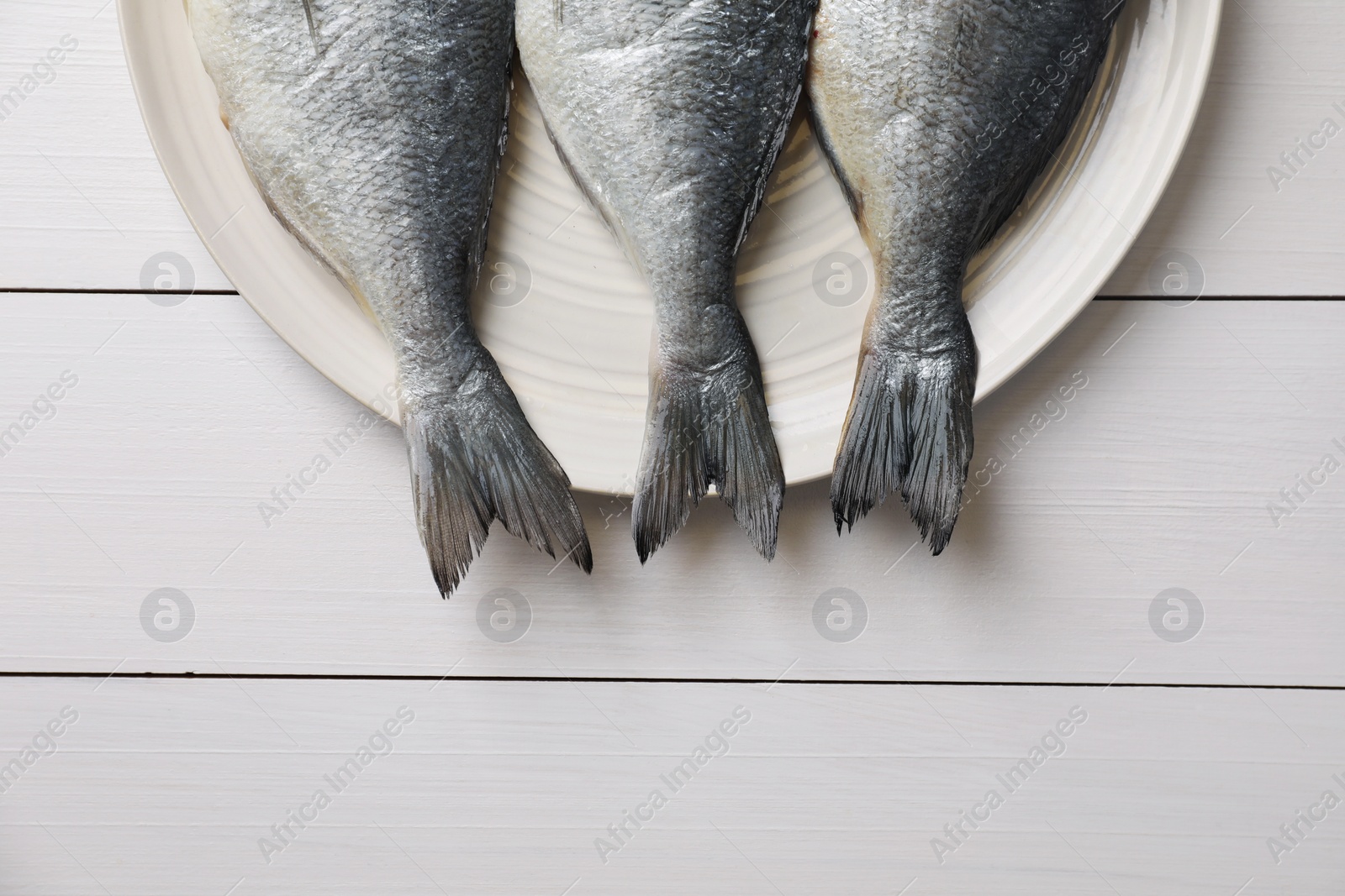 Photo of Fresh raw dorado fish on white wooden table, top view. Space for text