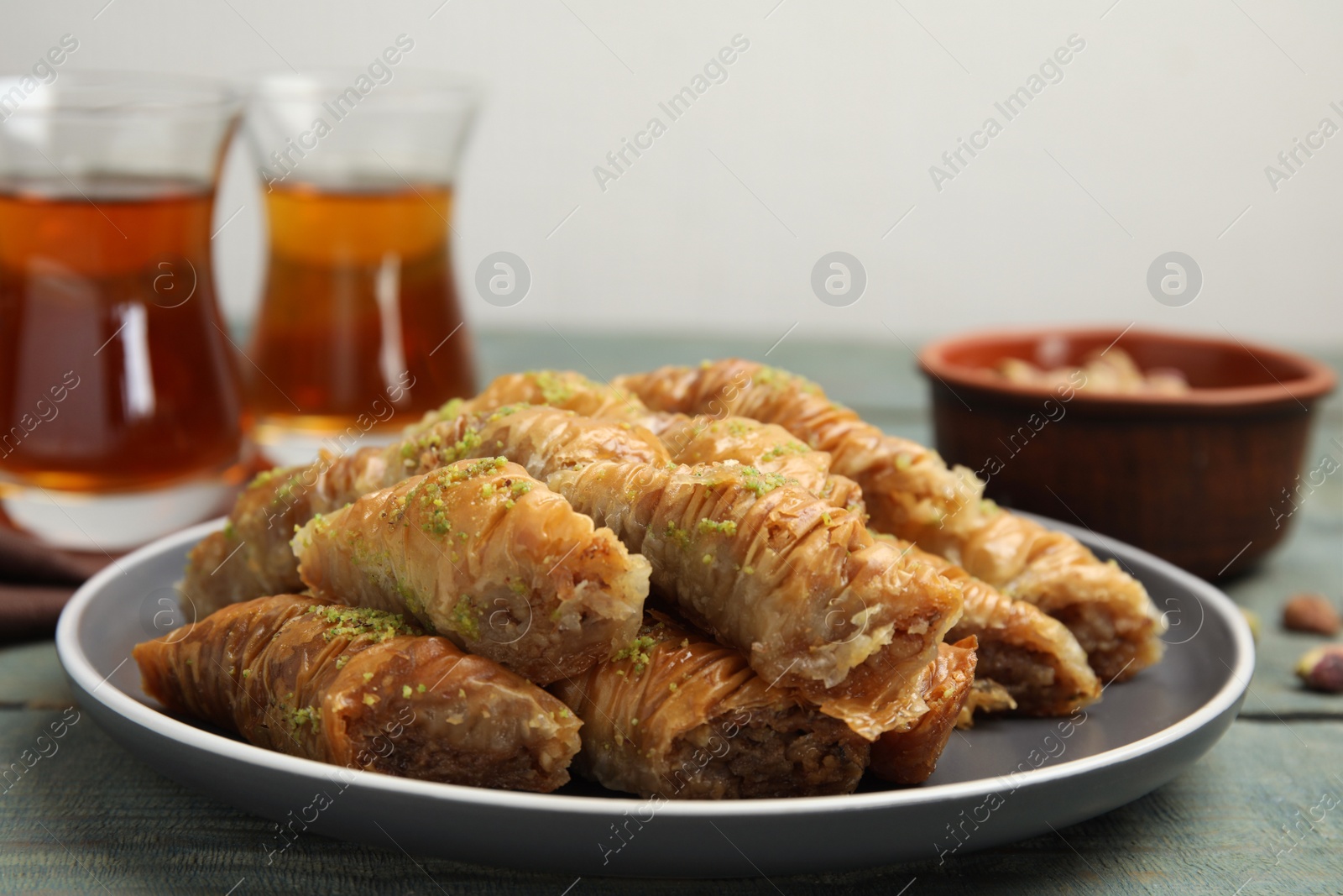 Photo of Delicious baklava with pistachios on light blue wooden table, closeup