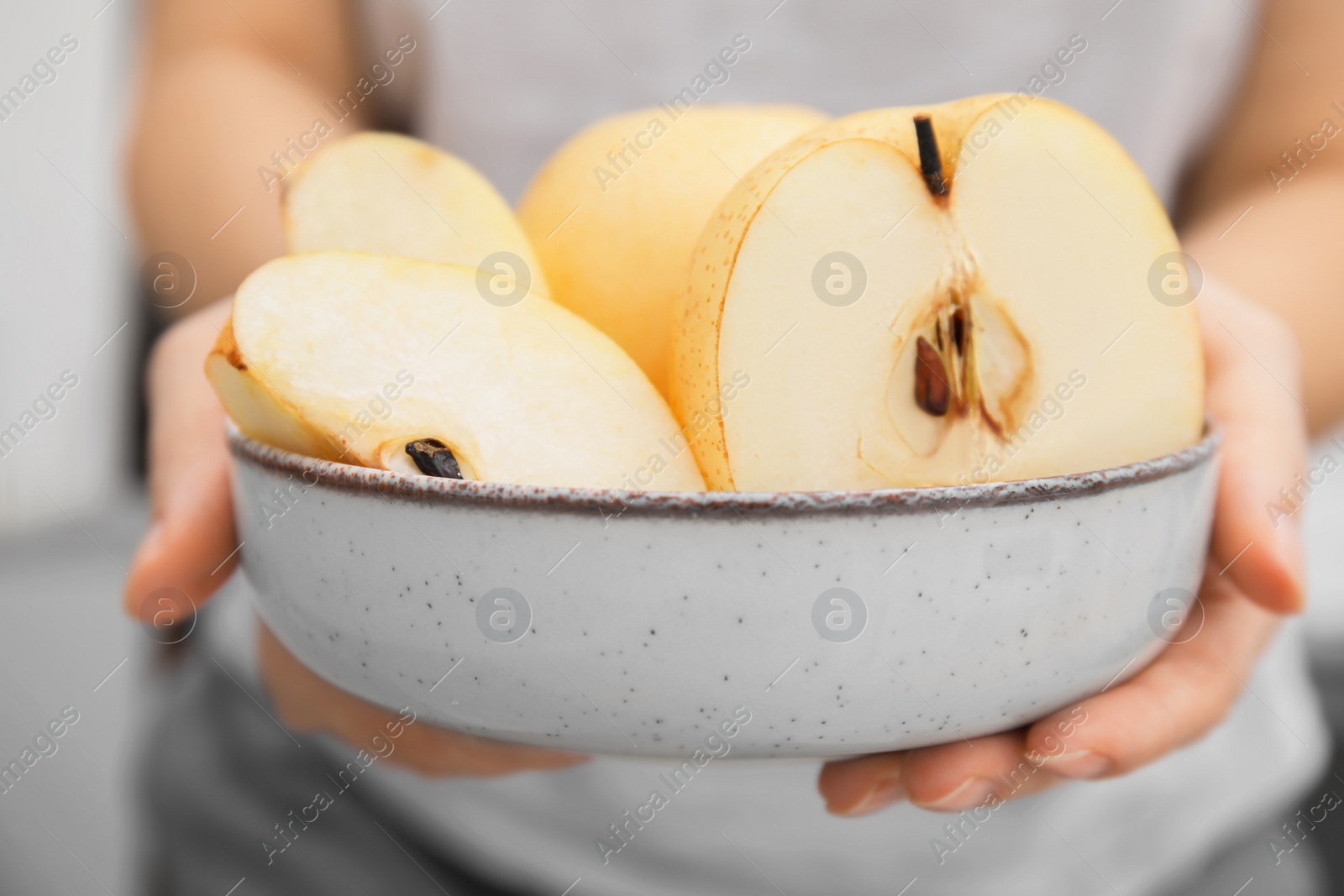 Photo of Woman holding bowl with fresh cut apple pears, closeup