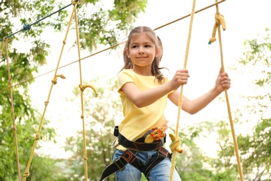 Little girl climbing in adventure park. Summer camp