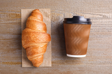 Photo of Tasty croissant and drink on wooden table, flat lay