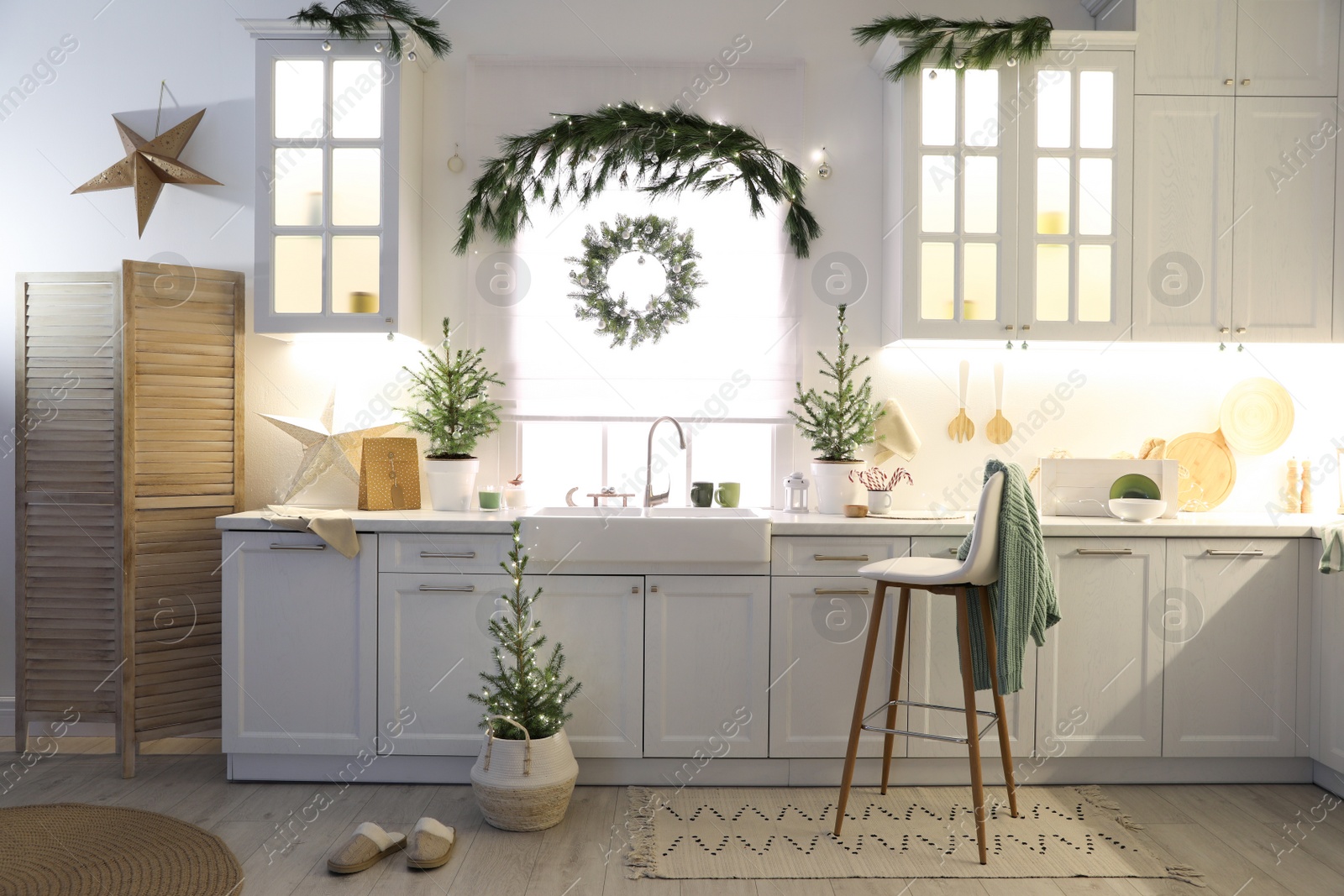 Photo of Small Christmas trees and festive decor in kitchen