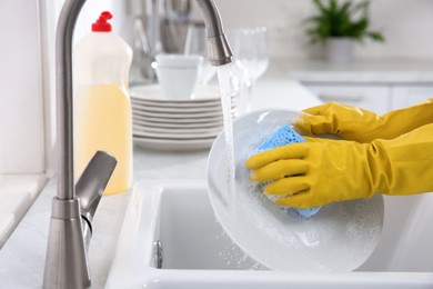 Photo of Woman washing plate in modern kitchen, closeup