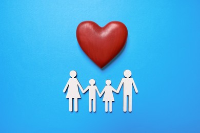 Photo of Figures of family and heart on light blue background, flat lay. Insurance concept
