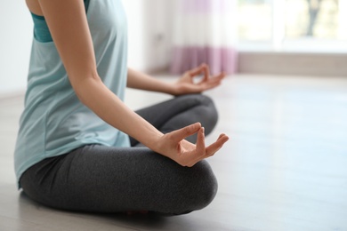 Photo of Young woman meditating indoors, closeup with space for text. Zen concept