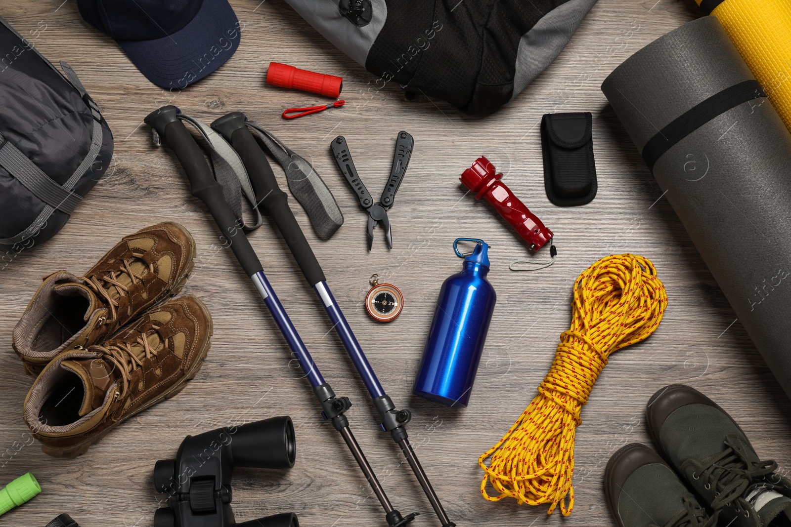 Photo of Flat lay composition with trekking poles and other hiking equipment on wooden background