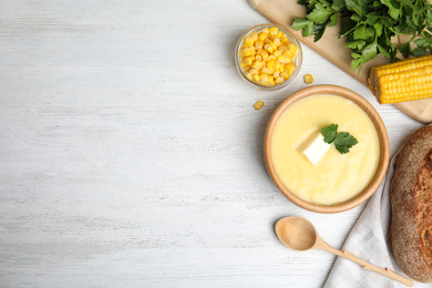 Delicious corn cream soup served on white wooden table, flat lay. Space for text