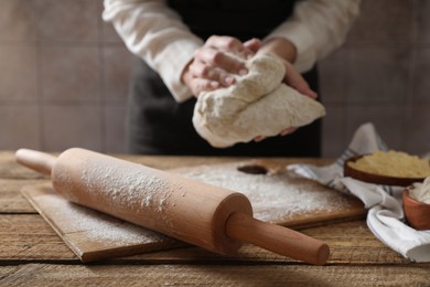 Photo of Woman making dough at wooden table, selective focus