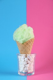 Photo of Sweet cotton candy in waffle cone on color background