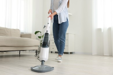 Woman cleaning floor with steam mop at home, closeup