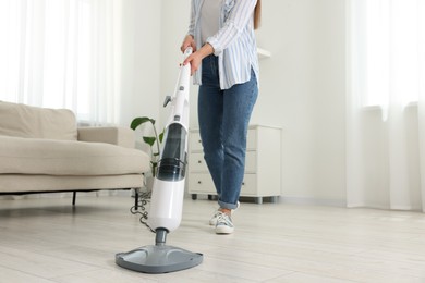 Photo of Woman cleaning floor with steam mop at home, closeup