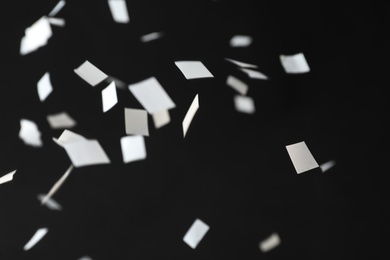 Photo of White confetti falling down on black background