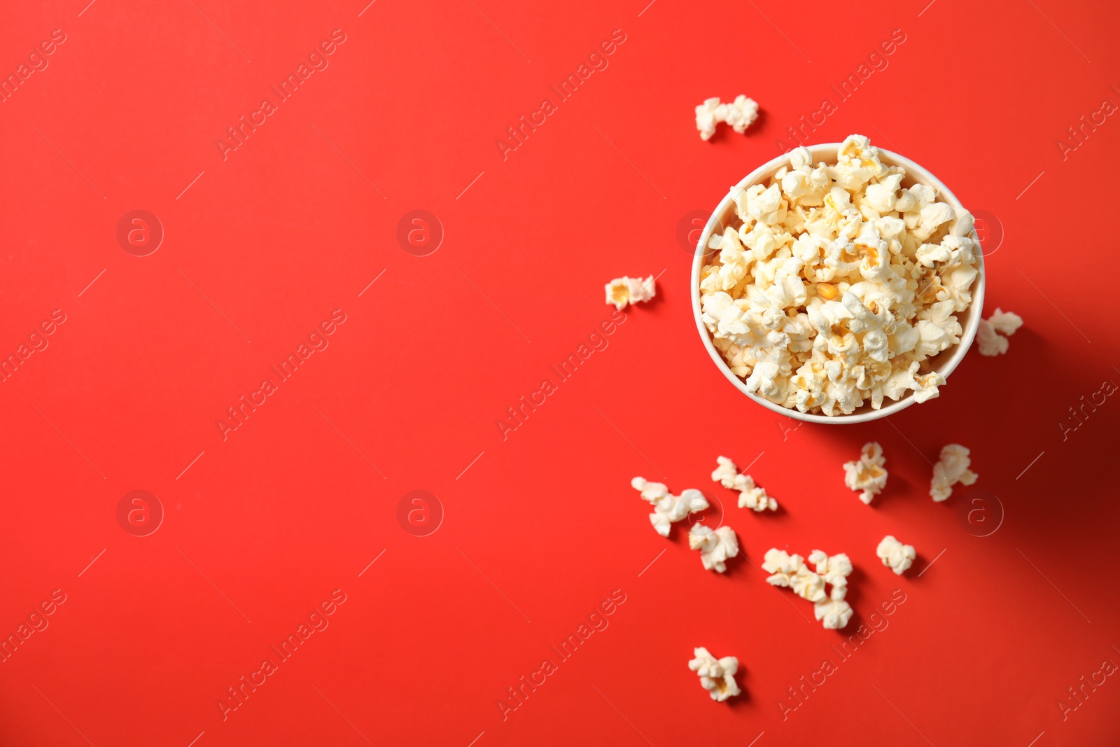 Photo of Fresh tasty popcorn and cup on color background, top view with space for text. Cinema snack