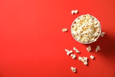 Fresh tasty popcorn and cup on color background, top view with space for text. Cinema snack