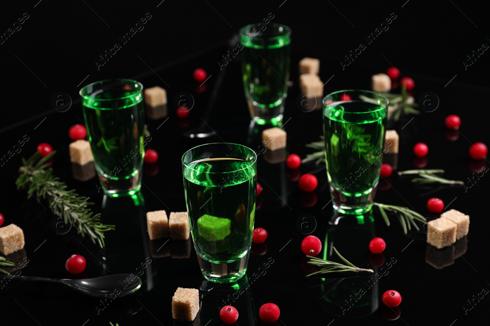 Photo of Absinthe in shot glasses, cranberries, rosemary and brown sugar on mirror table. Alcoholic drink