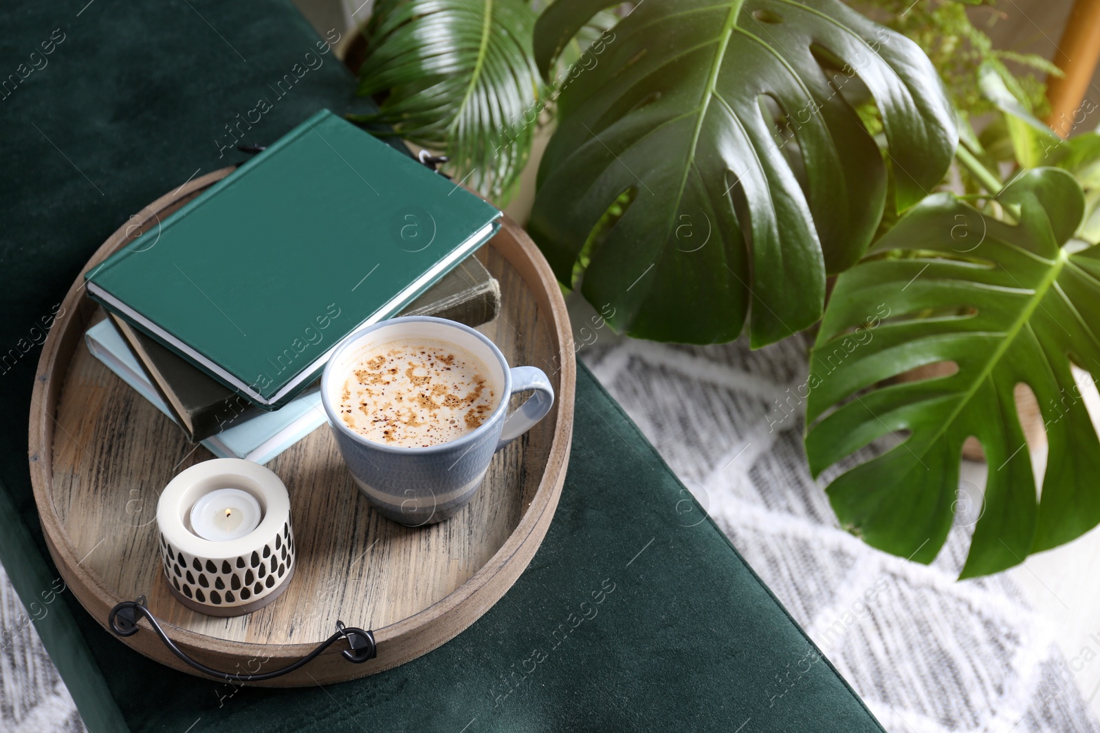 Photo of Wooden tray with books, coffee and candle on bench indoors