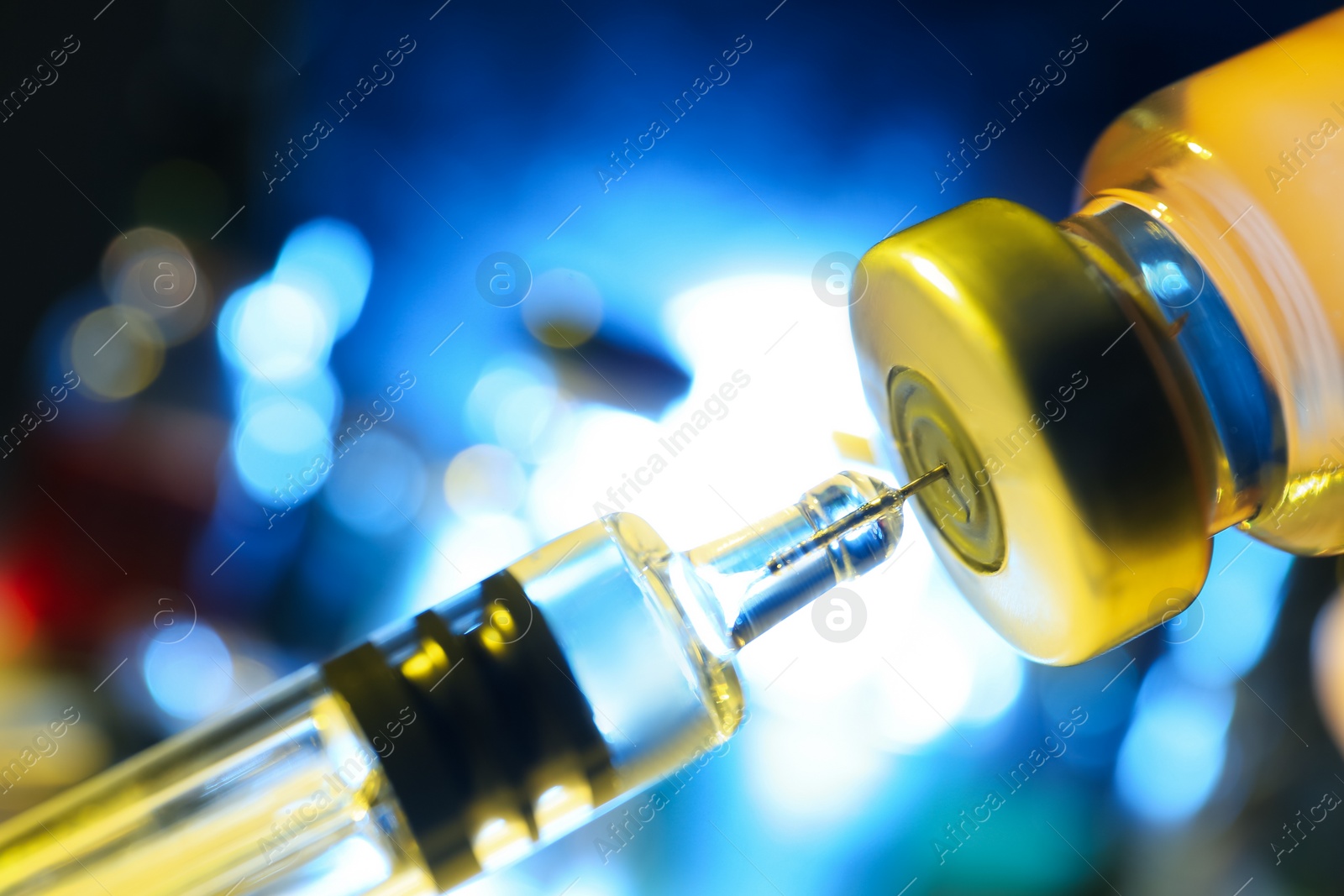 Photo of Filling syringe with vaccine from vial on blurred background, closeup