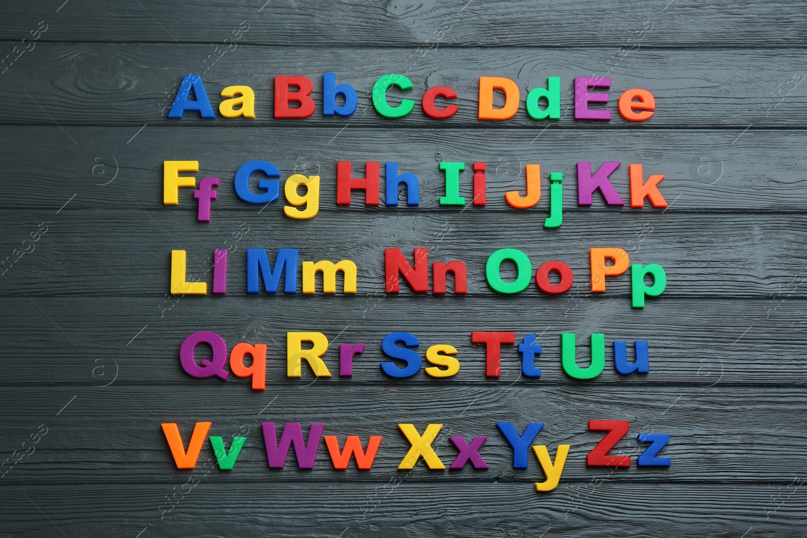 Photo of Colorful magnetic letters on black wooden background, flat lay. Alphabetical order