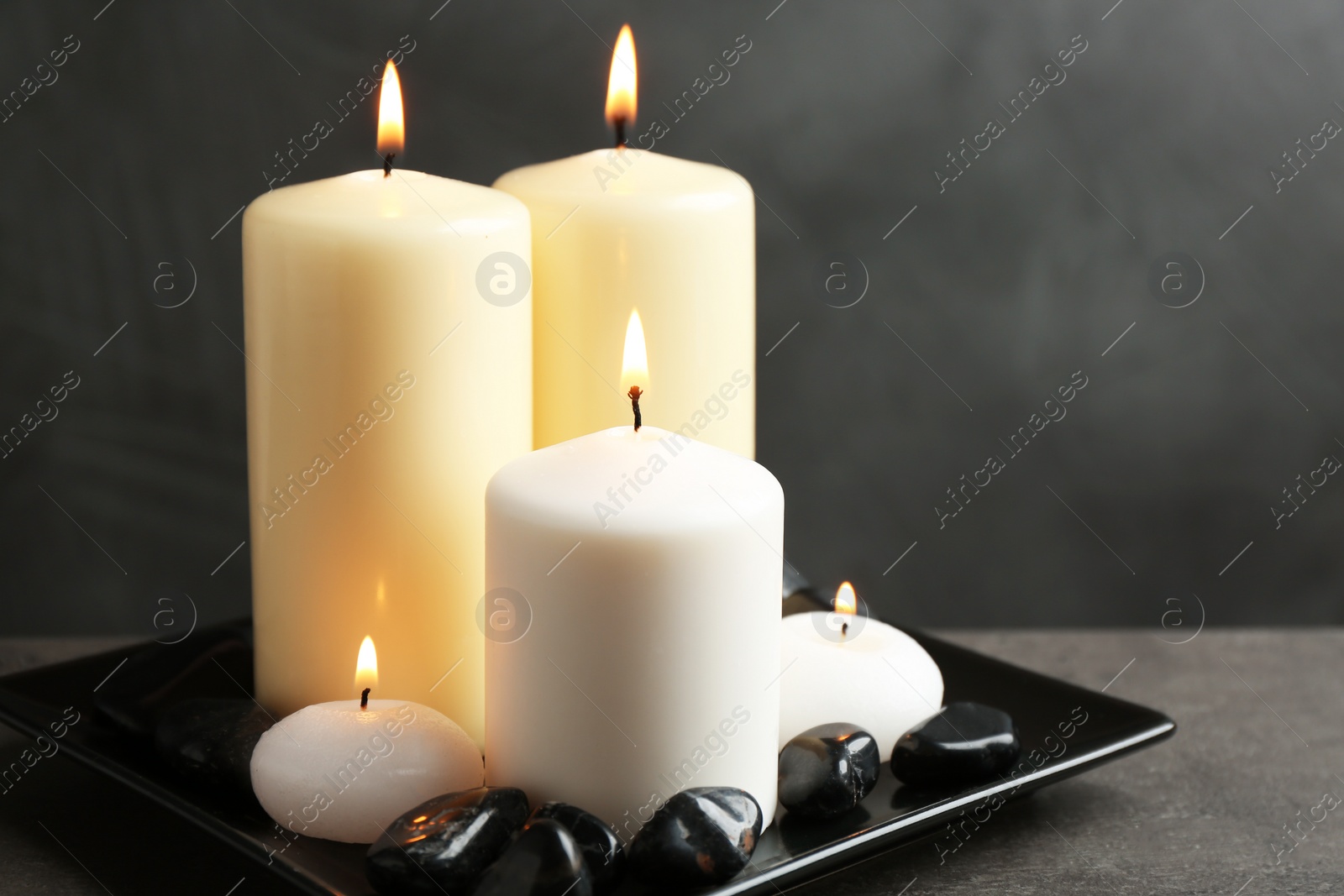 Photo of Plate with color candles and rocks on table, space for text