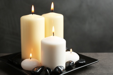 Photo of Plate with color candles and rocks on table, space for text