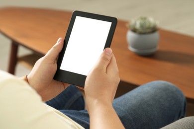 Photo of Man using e-book reader indoors, closeup view