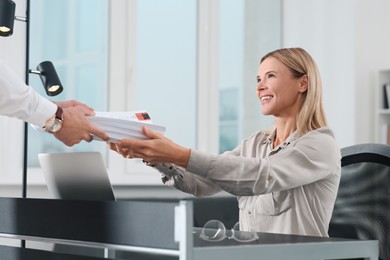 Photo of Man giving documents to happy colleague in office