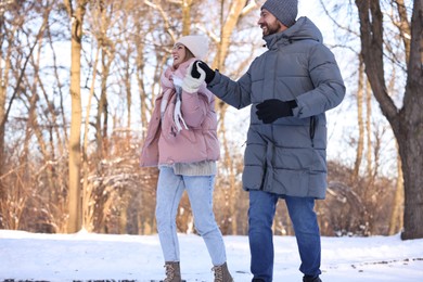 Photo of Happy couple walking in sunny snowy park, low angle view