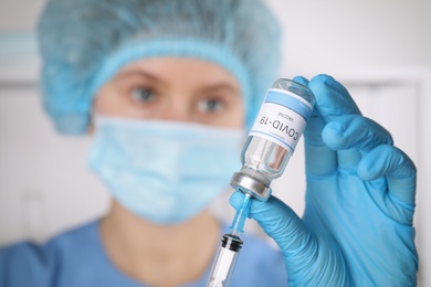 Photo of Doctor filling syringe with coronavirus vaccine in laboratory, focus on hand