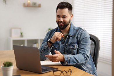 Young man using video chat during webinar at table in room