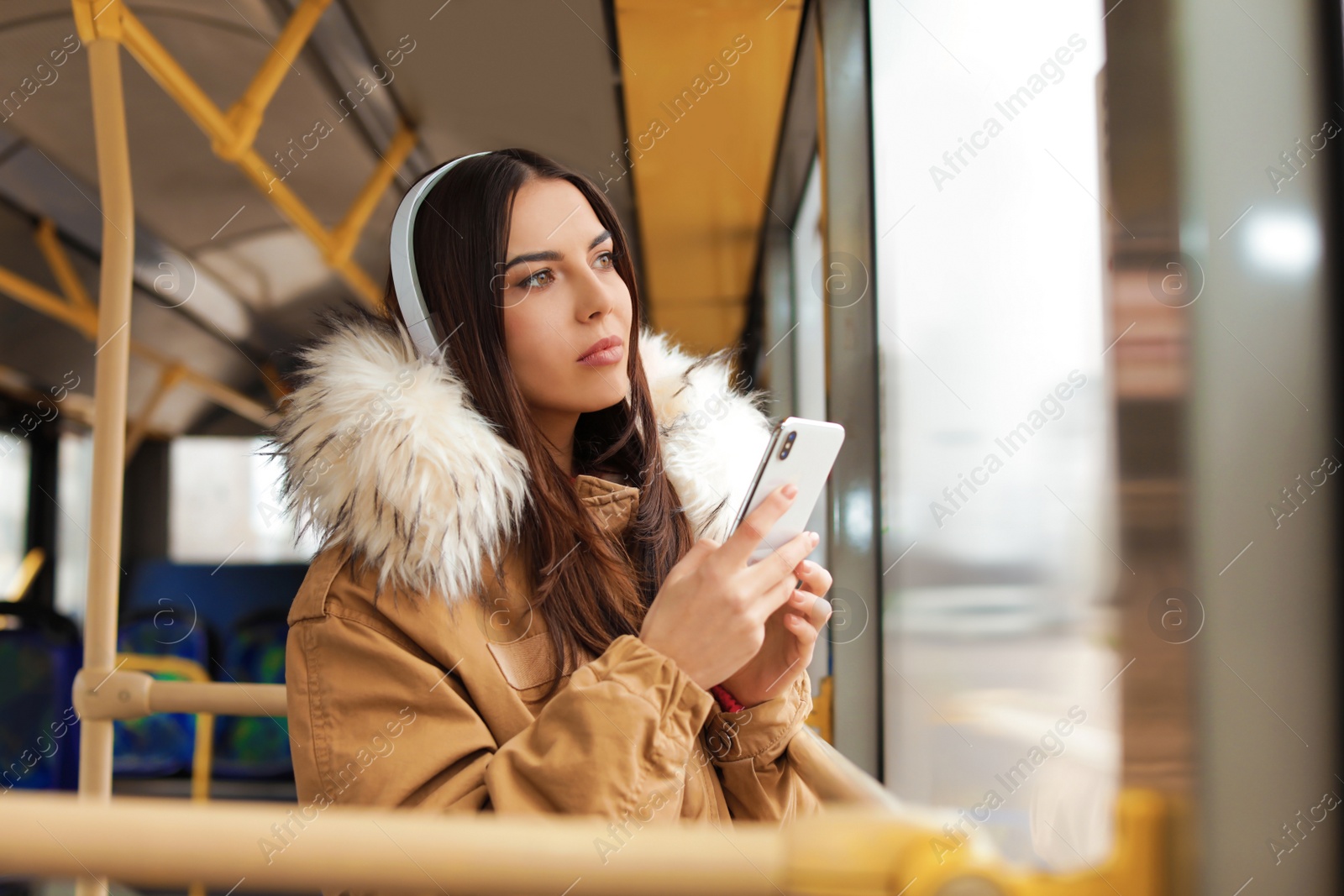 Photo of Young woman listening to music with headphones in public transport