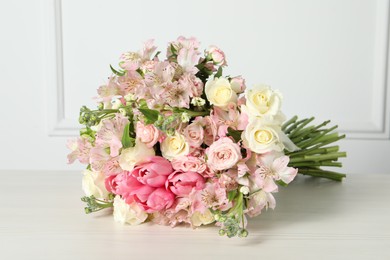 Photo of Beautiful bouquet of fresh flowers on table near white wall