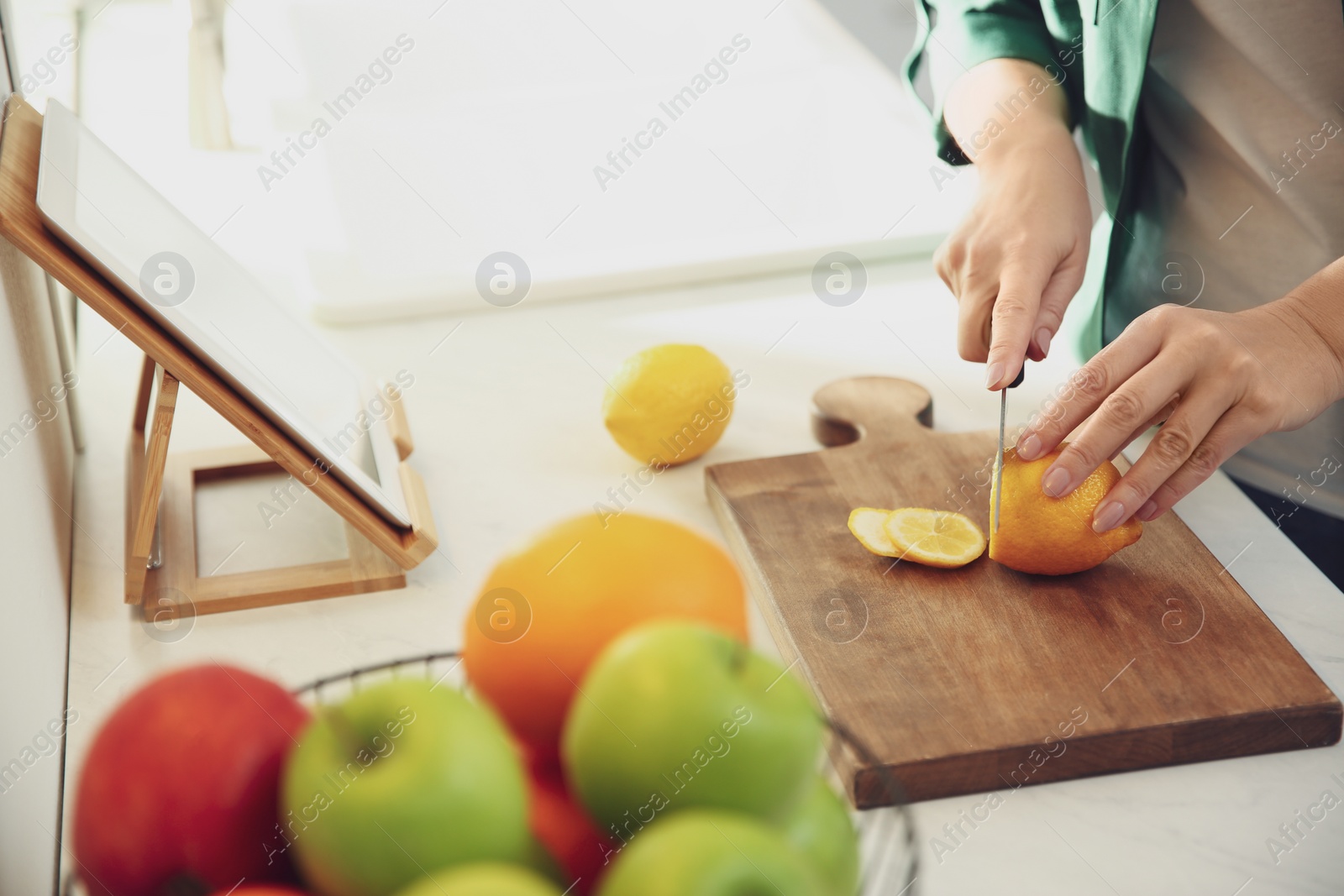 Photo of Woman with tablet cooking at table in kitchen, closeup