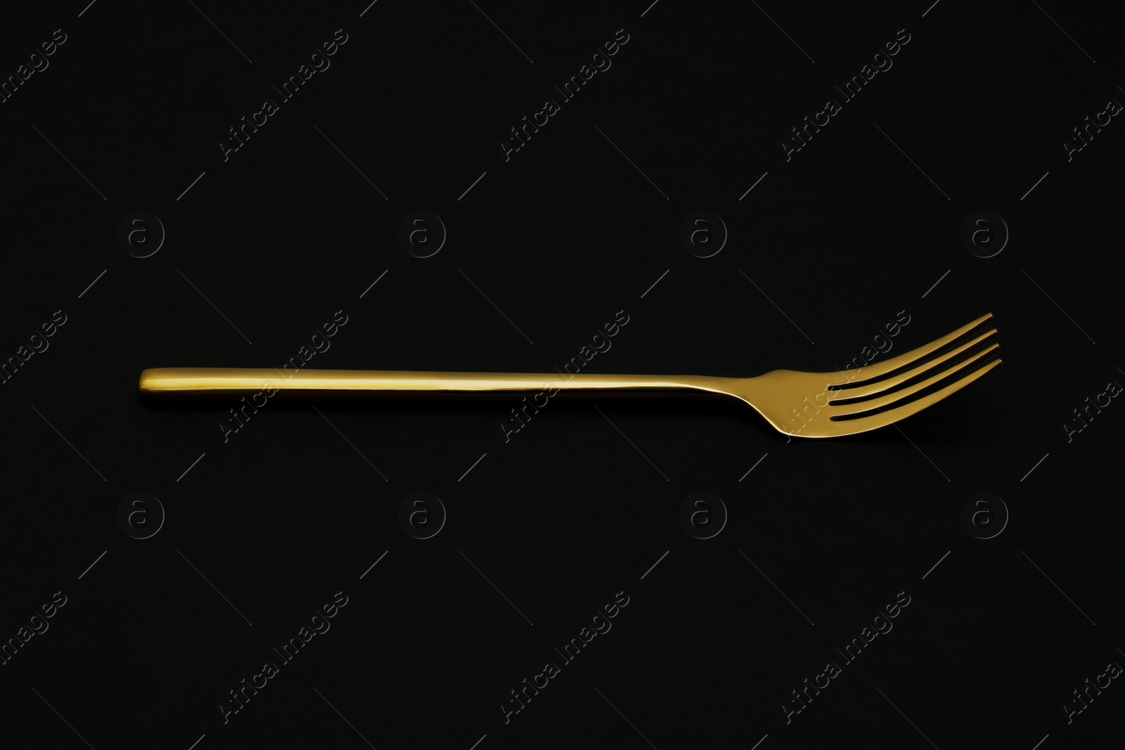 Photo of Shiny elegant gold fork on black background