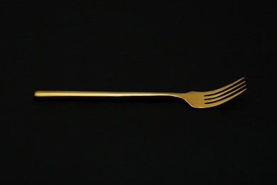 Shiny elegant gold fork on black background