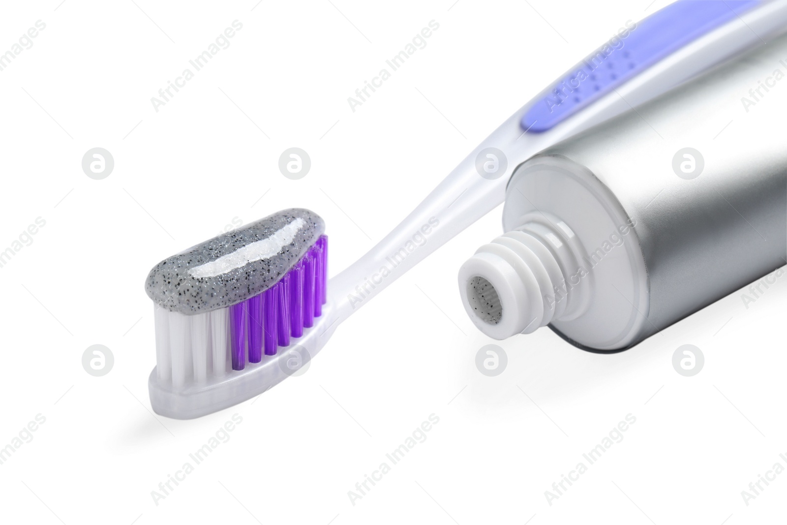 Photo of Tube of charcoal toothpaste and brush on white background