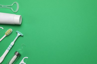 Photo of Flat lay composition with tongue cleaners and teeth care products on green background, space for text