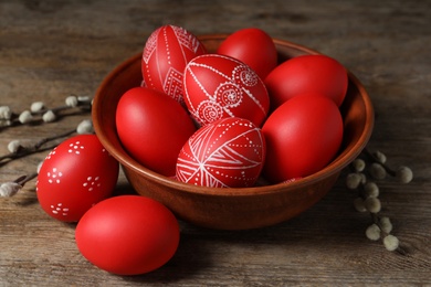 Photo of Wooden bowl with red painted Easter eggs on table