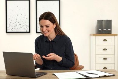 Woman having video chat via laptop at wooden table in office