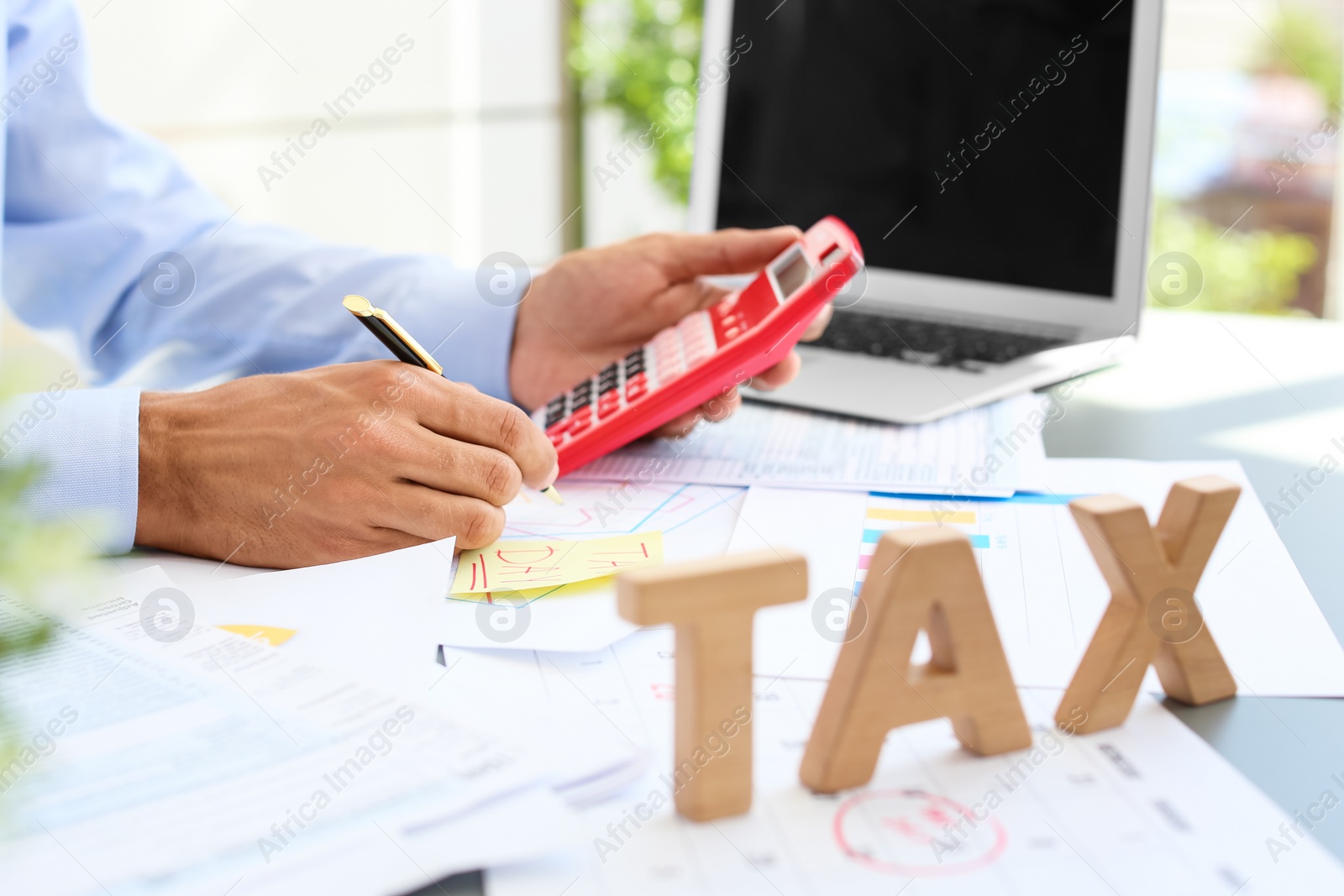 Photo of Tax accountant working with calculator at table