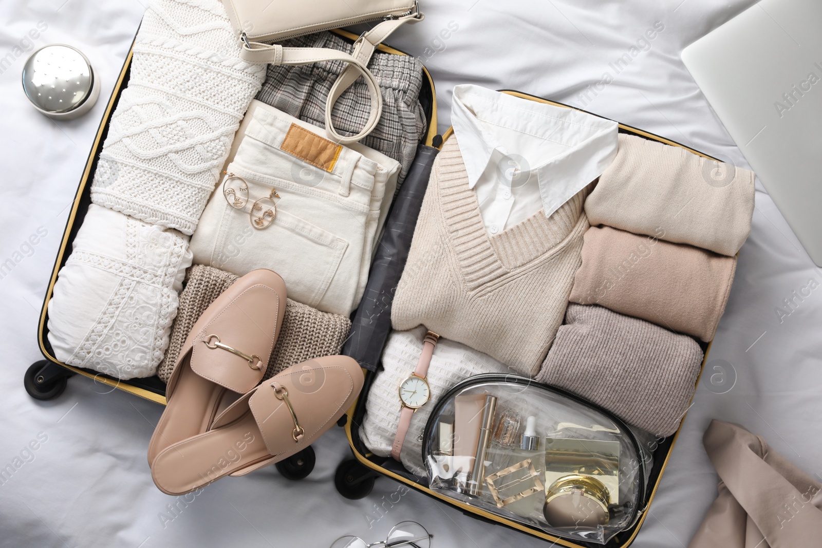 Photo of Open suitcase with folded clothes, shoes and accessories on bed, top view