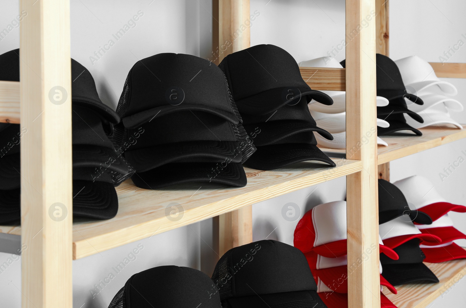 Photo of Wooden rack with different blank caps in store. Mock up for design