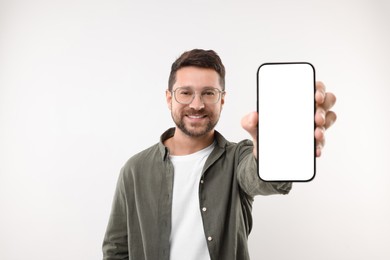 Photo of Handsome man showing smartphone in hand on white background