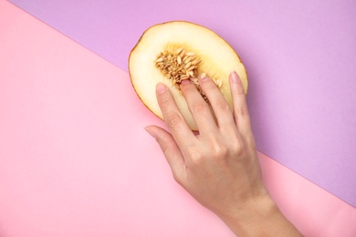 Photo of Young woman touching half of melon on color background, flat lay. Sex concept